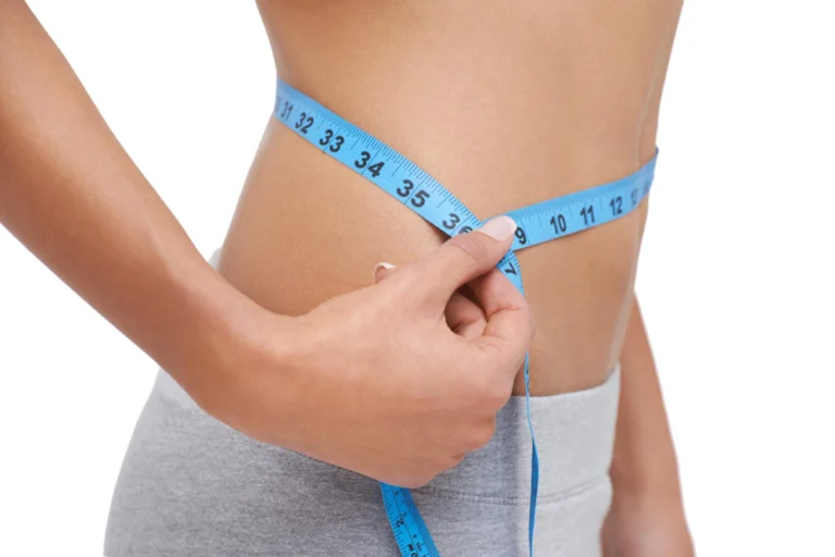 Photo looking great studio shot of a woman measuring her waistline