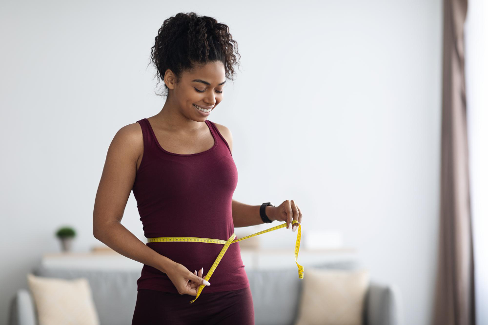 Slim african american woman in sportswear measuring waist