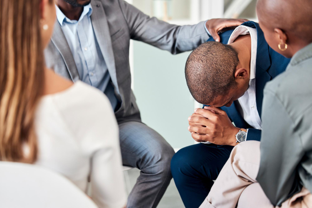 Group therapy support and counseling with a business man and team in a meeting for emotions or healing Mental health psychology and rehabilitation with a male employee in a session for growth