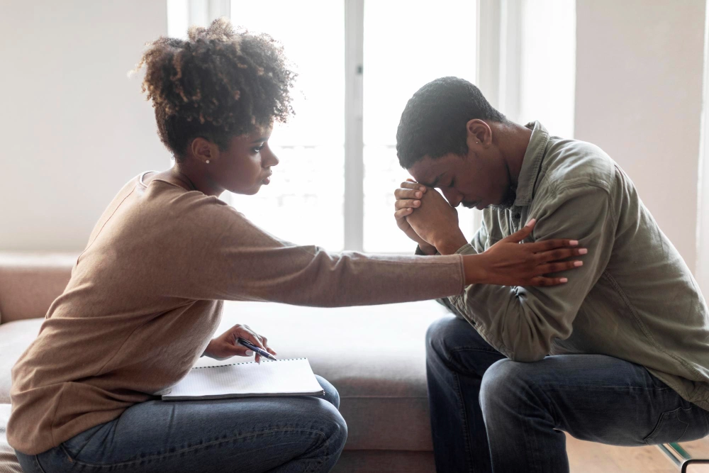 Black woman psychologist comforting man patient with Healing from Trauma side view