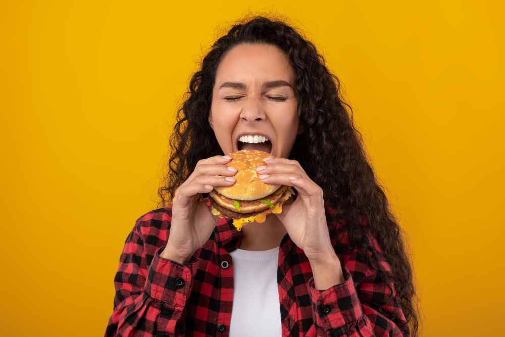 Funny latin lady holding burger biting sandwich at studio