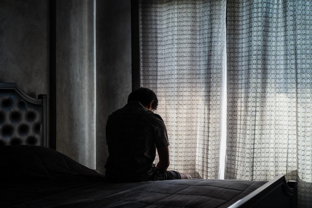 man with depression sitting on bed