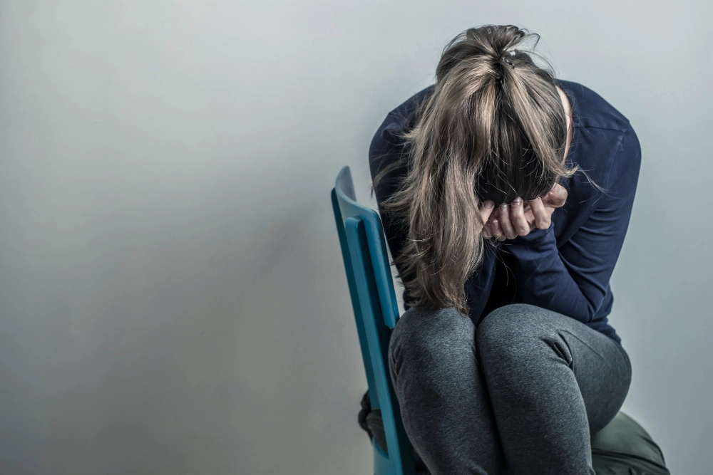 Depressive and desperate girl sits on a chair. Sad young woman